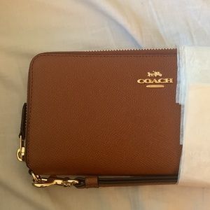 Brown coach wallet never used, in original packaging. With leather hand strap.